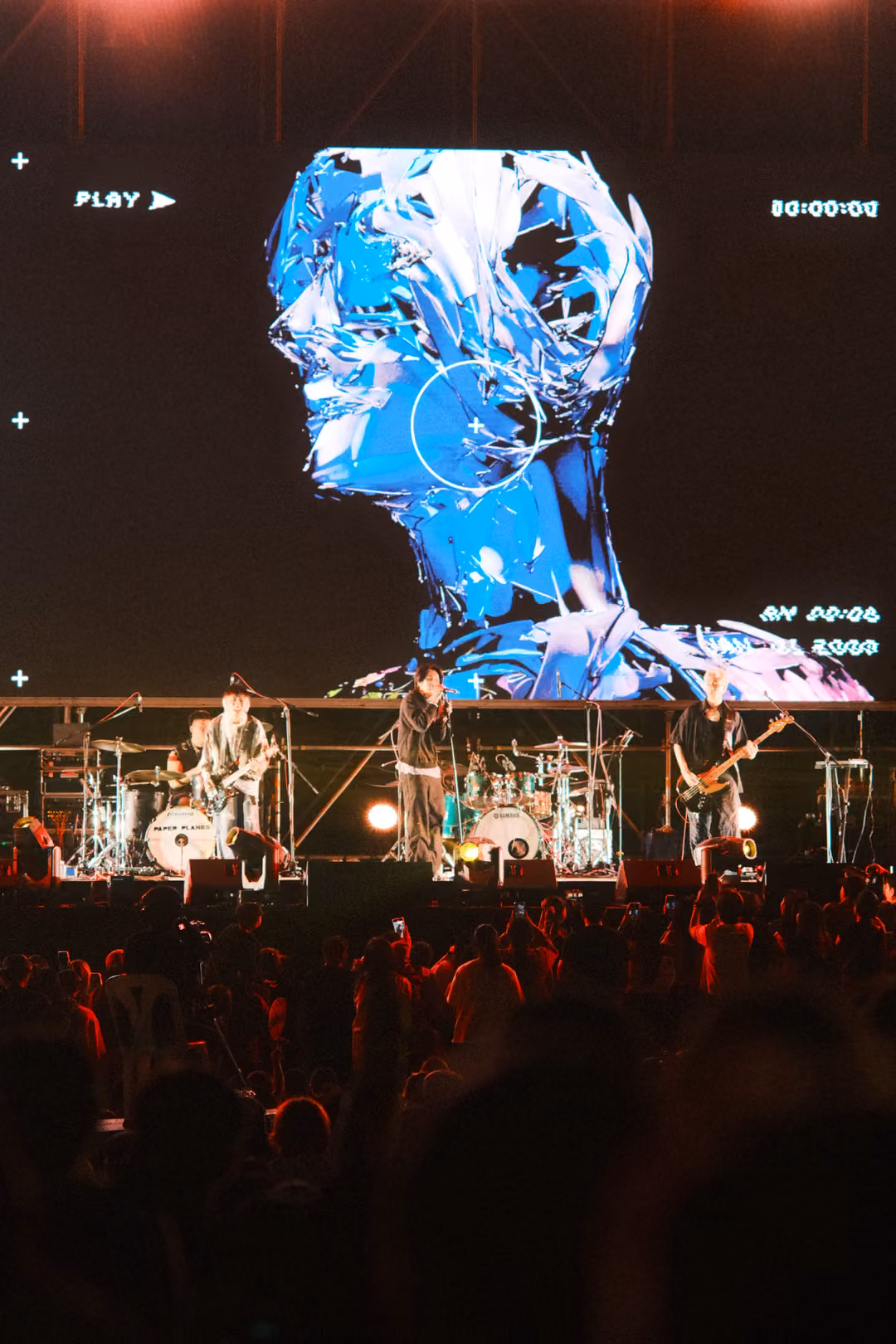 Vertical view of a screen showing a blue sculpted head with a crosshair, PLAY label and timestamps, band below.