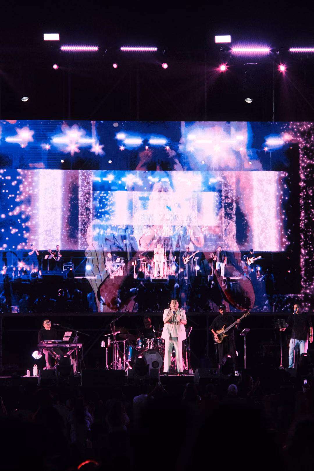 Vertical frame of the stage with a screen of blue starbursts and sparkles, a smaller image of the stage within it
