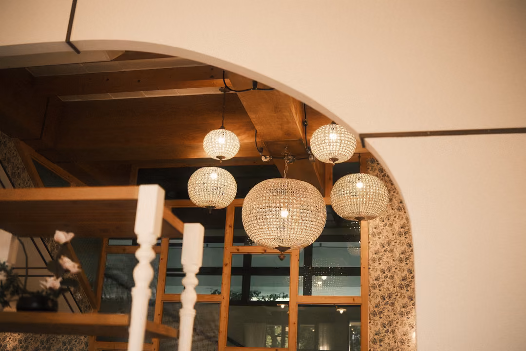 Cream archway framing woven globe pendant lights above a wooden staircase with white turned balusters