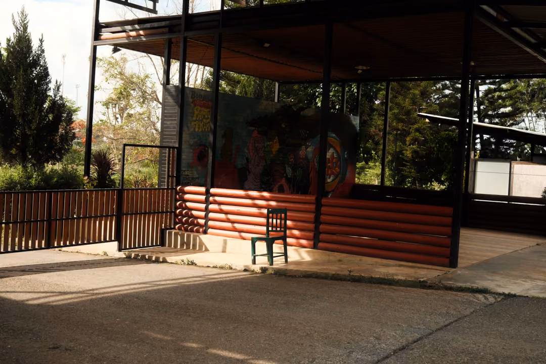 Open pavilion with a red log-style wall, a small green chair and a colourful painted mural