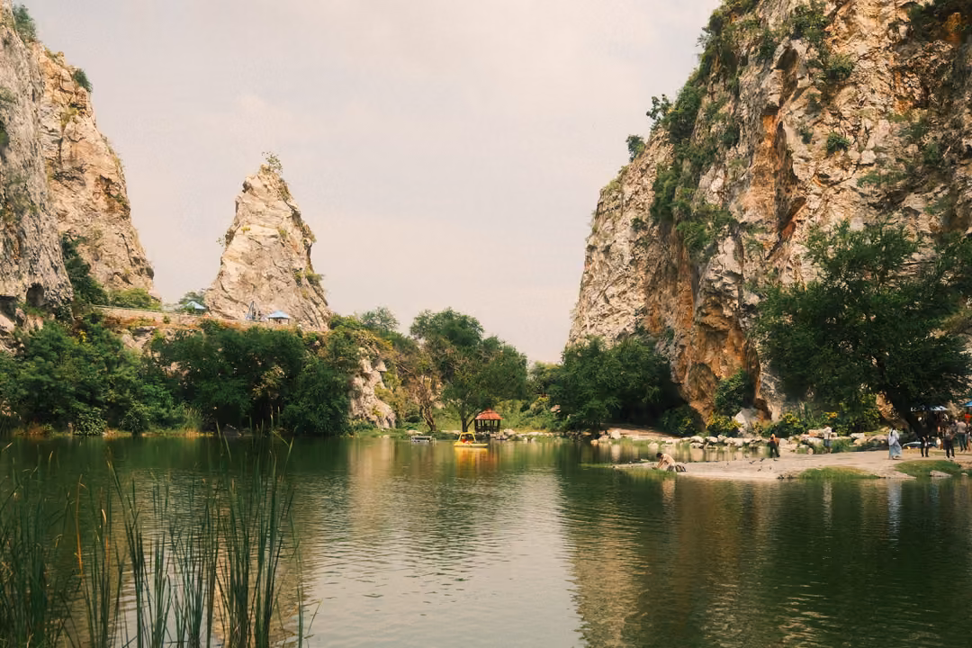 Lake with tall reeds in the foreground, a pointed rock spire and cliffs reflected in the water