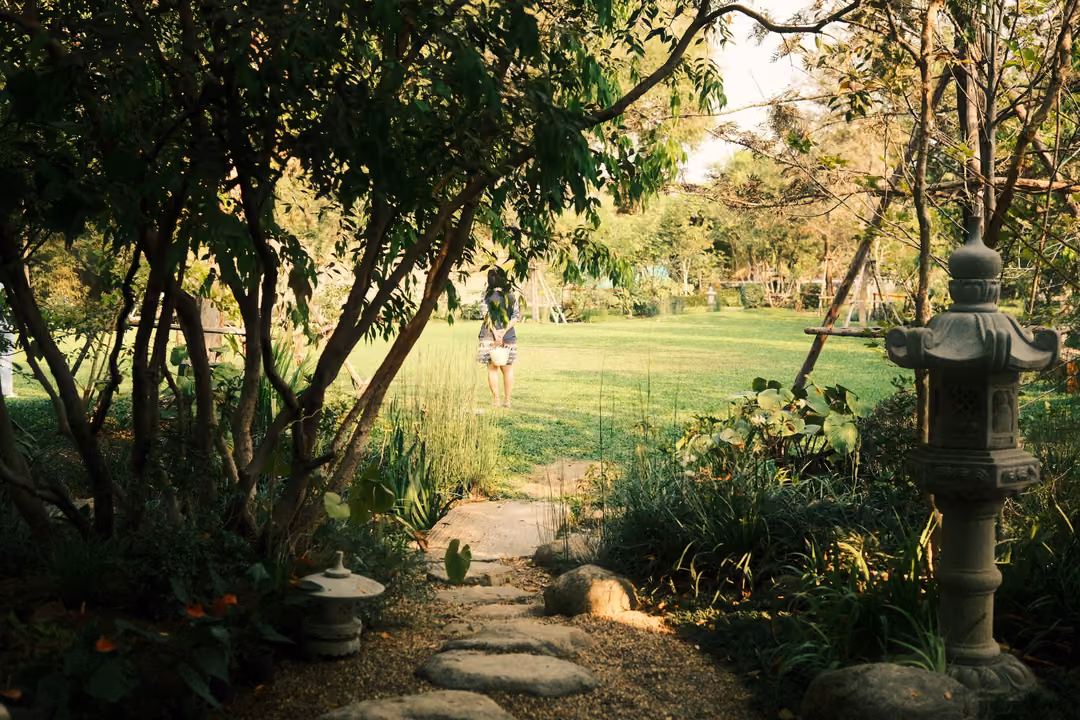 Garden path with stepping stones and a stone lantern leading to a wide lawn, a small figure far away