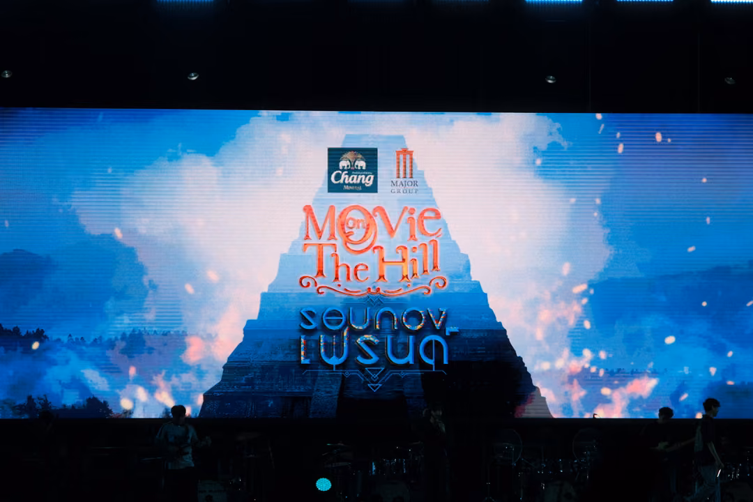 Wide screen showing the Movie on The Hill logo on a stepped pyramid shape amid clouds and orange sparks.