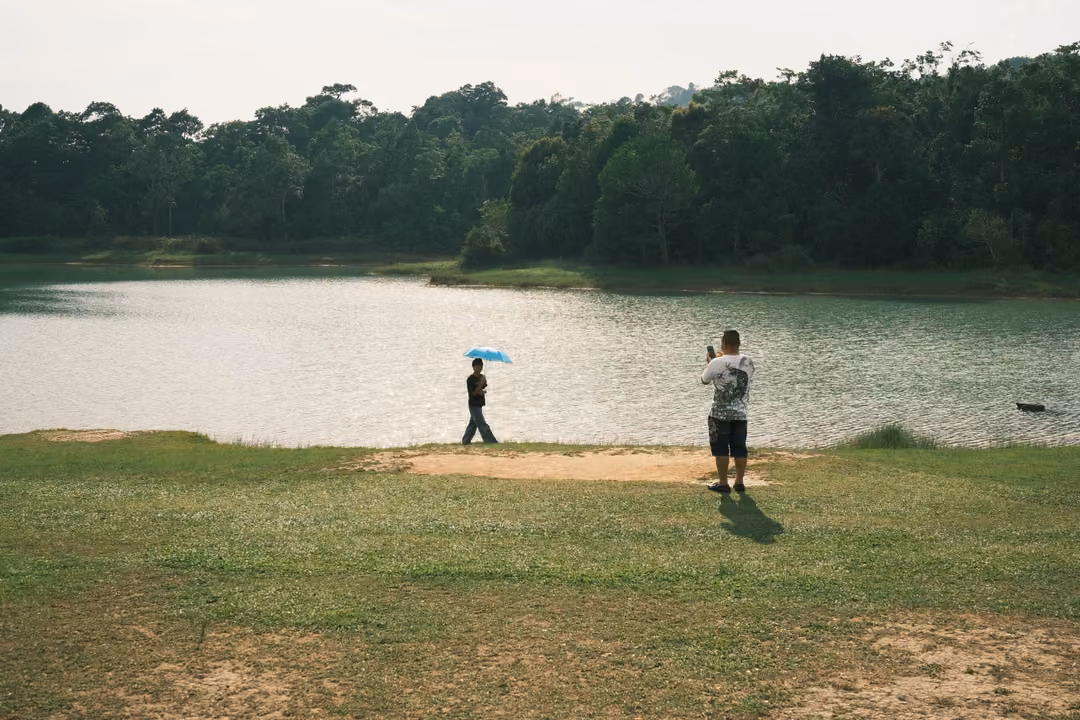 The same lakeside scene seconds later, the umbrella-holder walking on as the other keeps photographing.