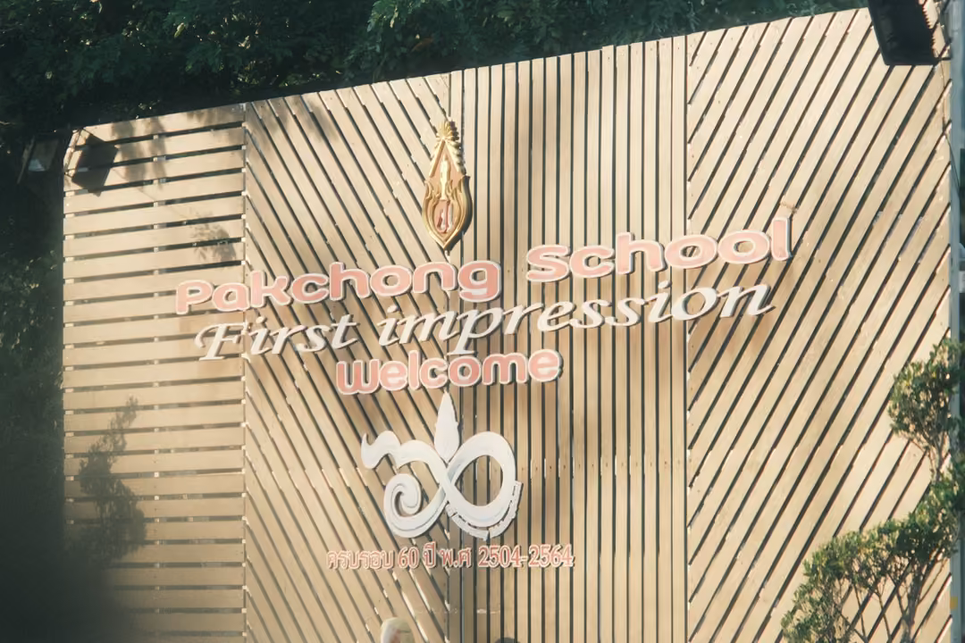 A slatted wooden welcome wall with a gold emblem and pink lettering reading First impression, Welcome.
