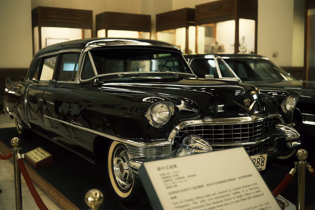 Polished black vintage car with chrome grille and whitewall tyres on display behind a red rope