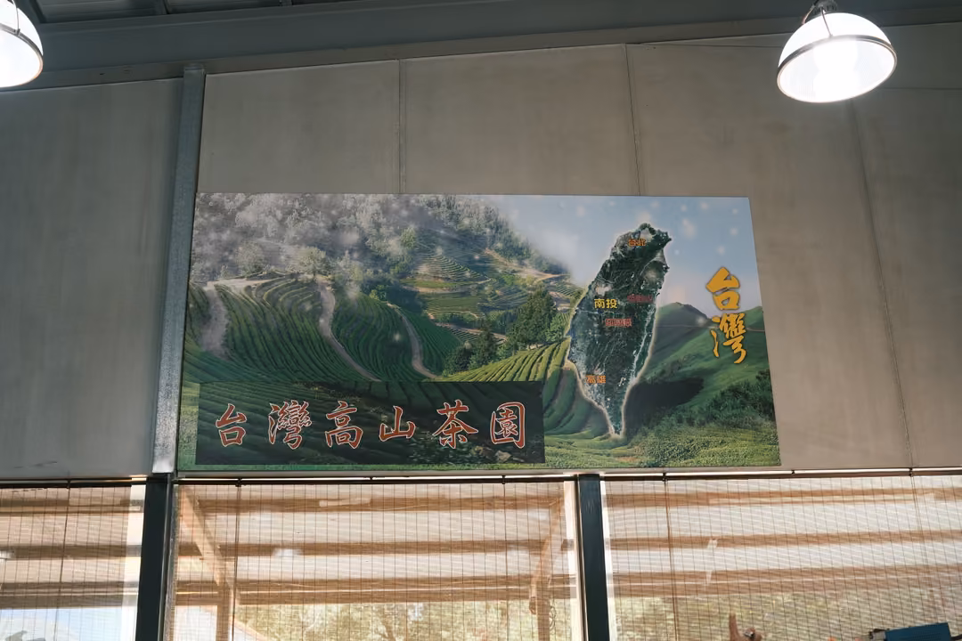 Wall poster of terraced tea fields and a map of Taiwan with red text reading 台灣高山茶園 under hanging lamps