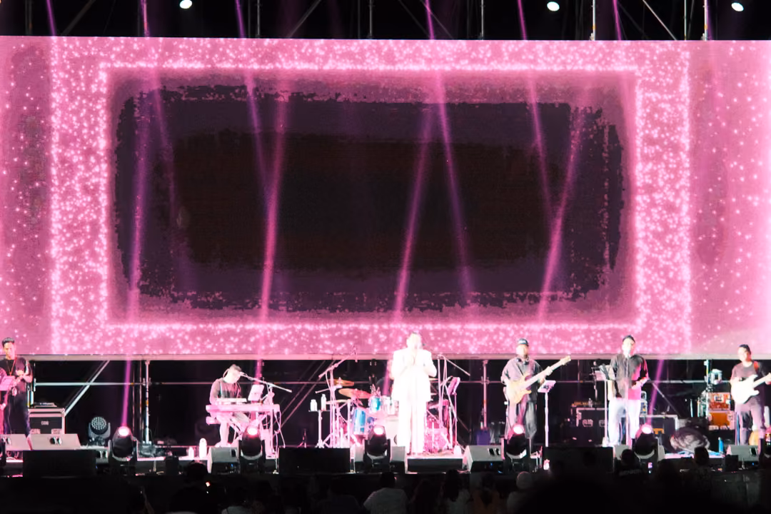 Pink, glittering frame on the big screen around an empty dark centre, full band lit on stage beneath