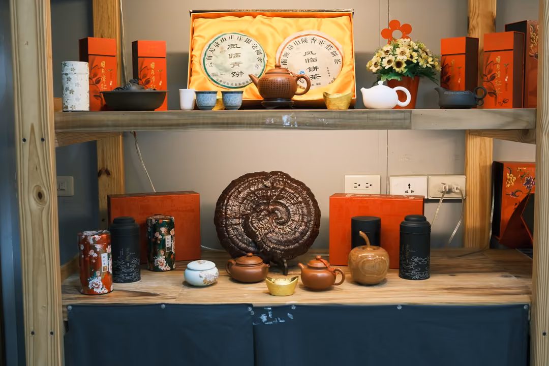 Wooden shelf with clay teapots, a round tea cake in a gold box, a large lingzhi-shaped object and red boxes