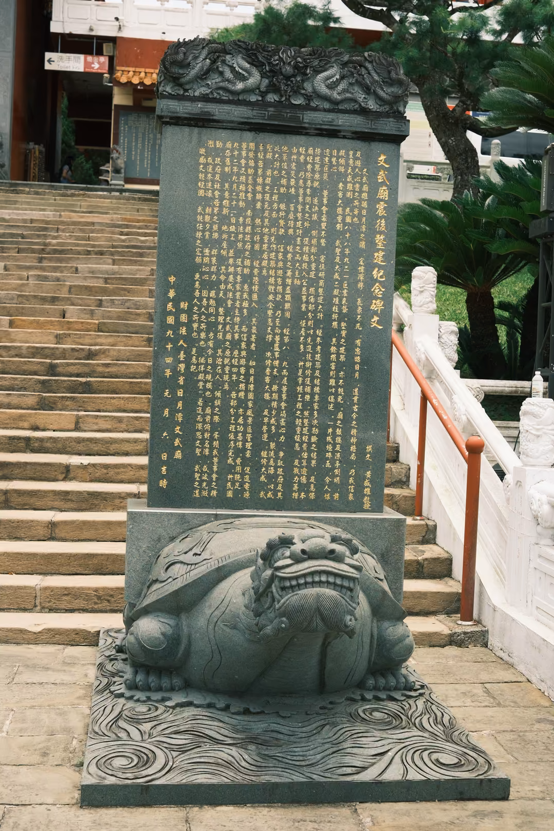 Inscribed stone tablet mounted on a carved turtle-like creature at the foot of a long staircase