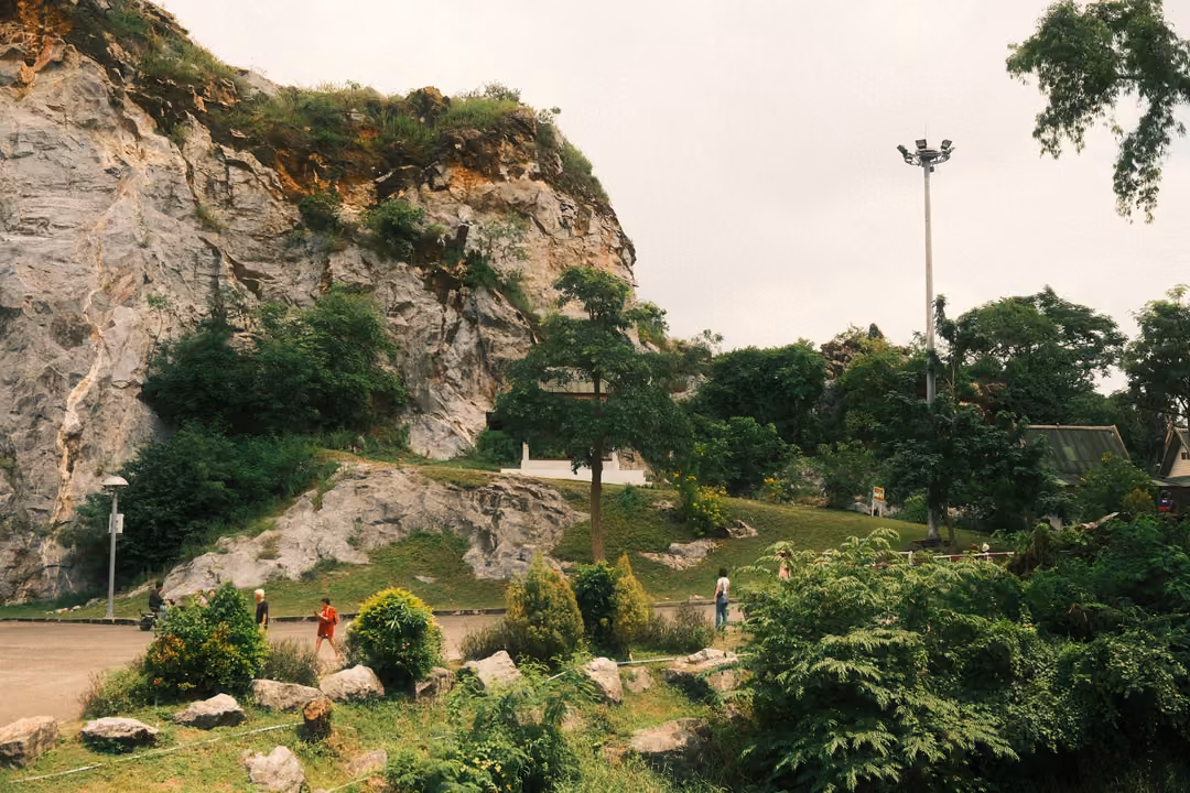 Limestone cliff above a landscaped garden with scattered rocks, shrubs and a tall lamp post