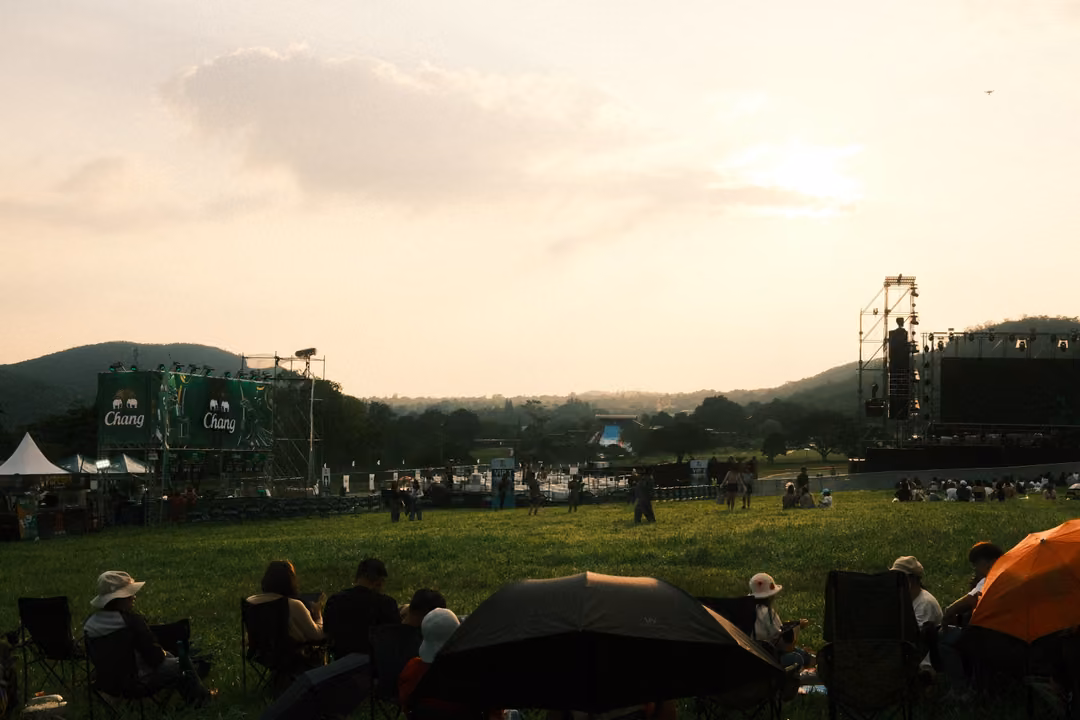 Chairs and umbrellas on a grassy hillside facing a stage, a black umbrella at the centre.