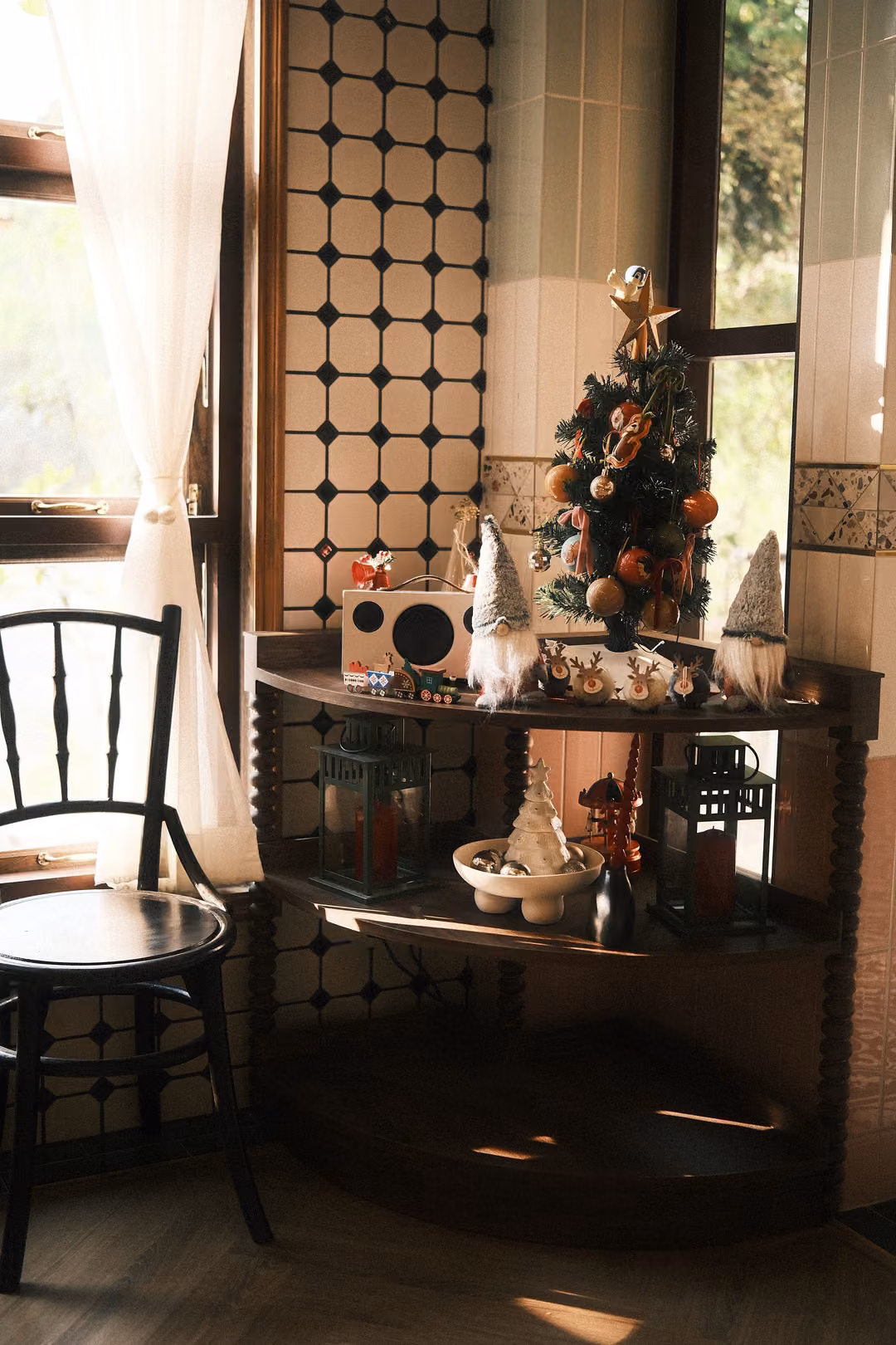 Corner shelf holding a small decorated Christmas tree, gnome figurines, a retro radio and lanterns