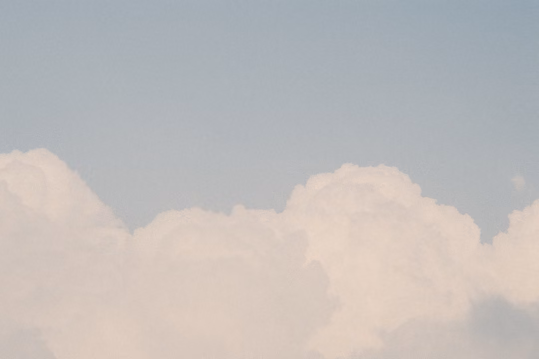 Wide band of cumulus clouds along the bottom of a pale blue-grey sky