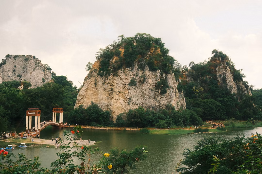 Lake with bridge towers and three limestone crags seen from above, flowering bushes in the foreground