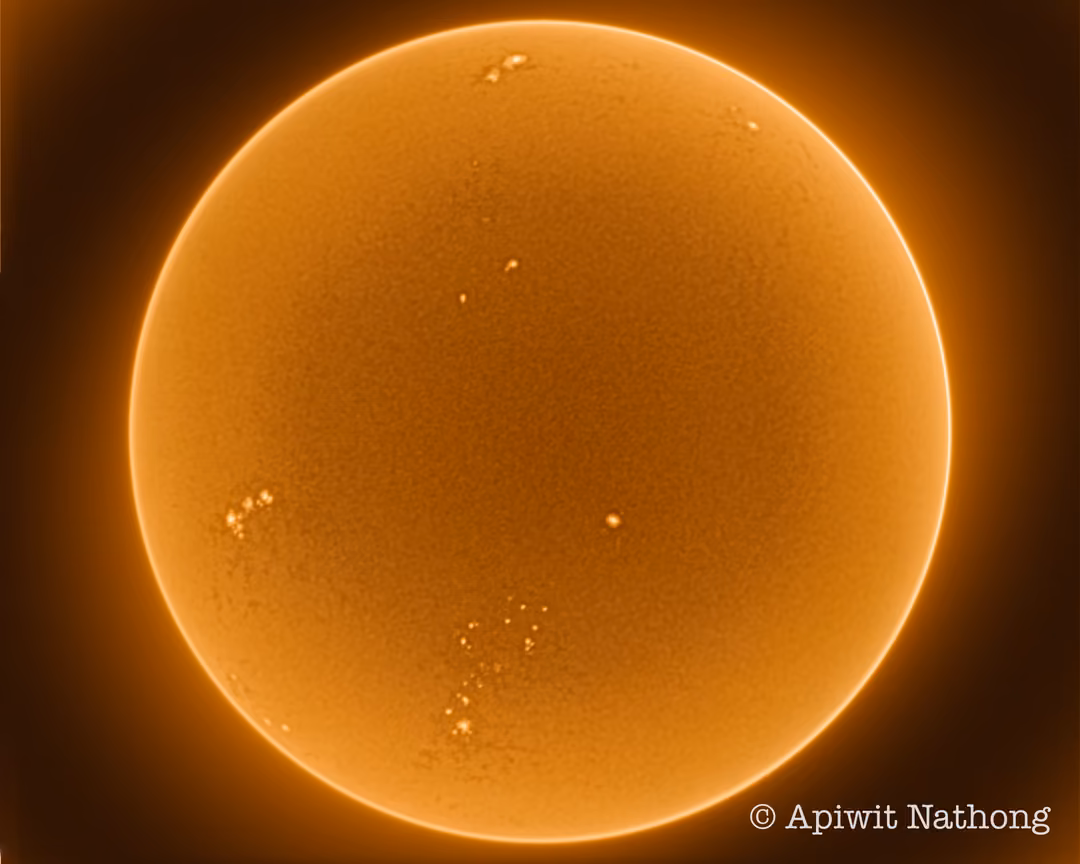 The full disc of the Sun in orange, its surface finely textured with bright spots near the edges