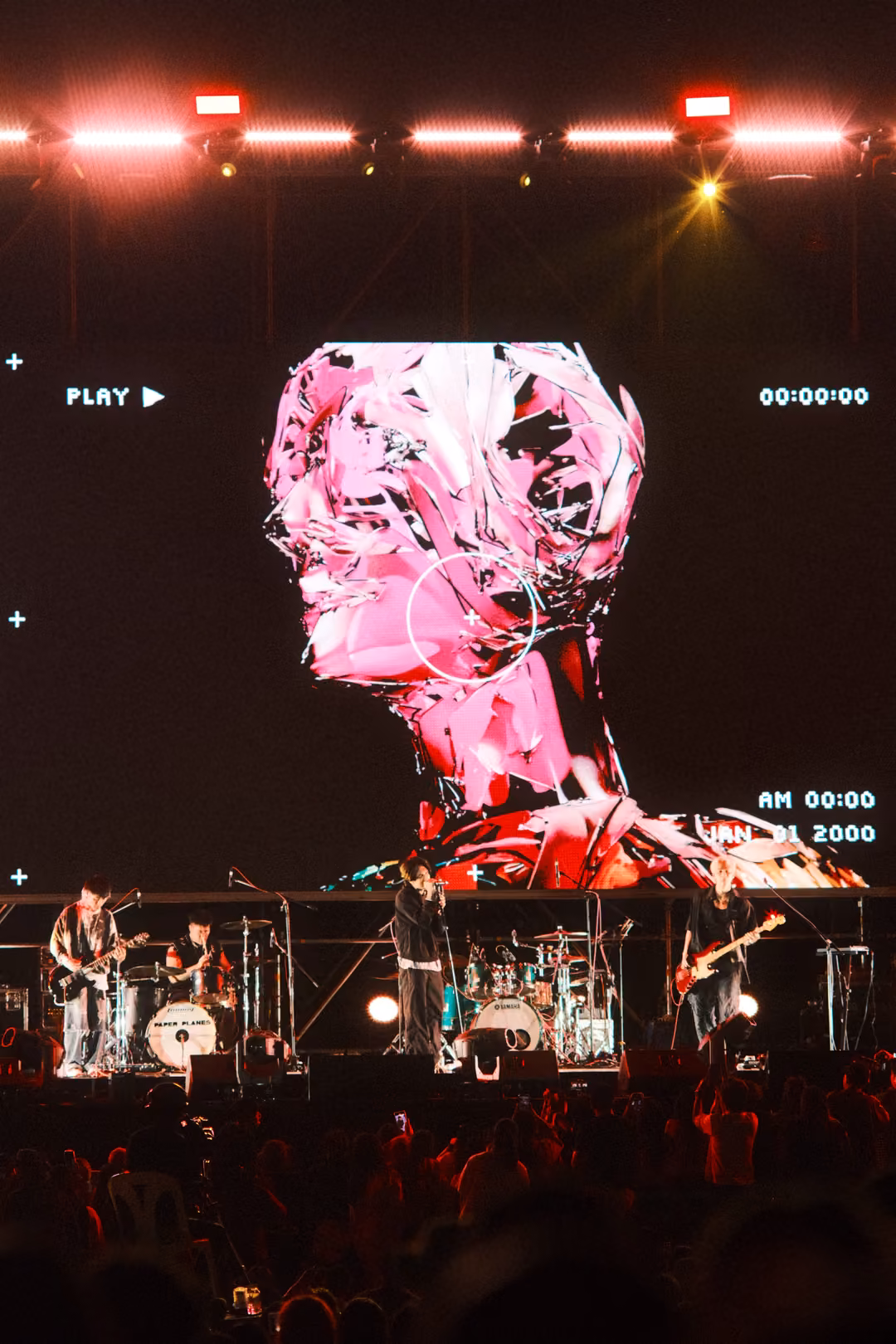Vertical view of a screen showing a magenta sculpted head with a crosshair circle, red and pink lights above, band below.