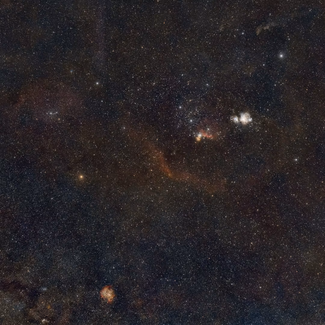 Wide starfield of Orion with a faint red arc of nebula, a bright white nebula and small red glows