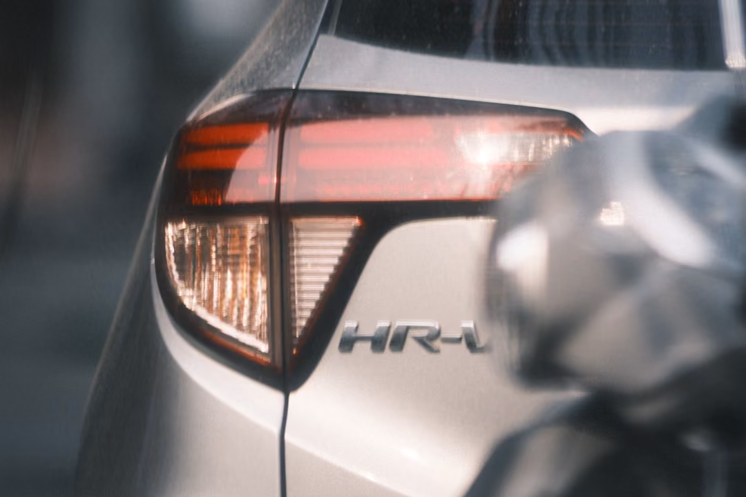 Close view of the tail light and HR-V badge on a silver car, a blurred grey shape in the foreground.