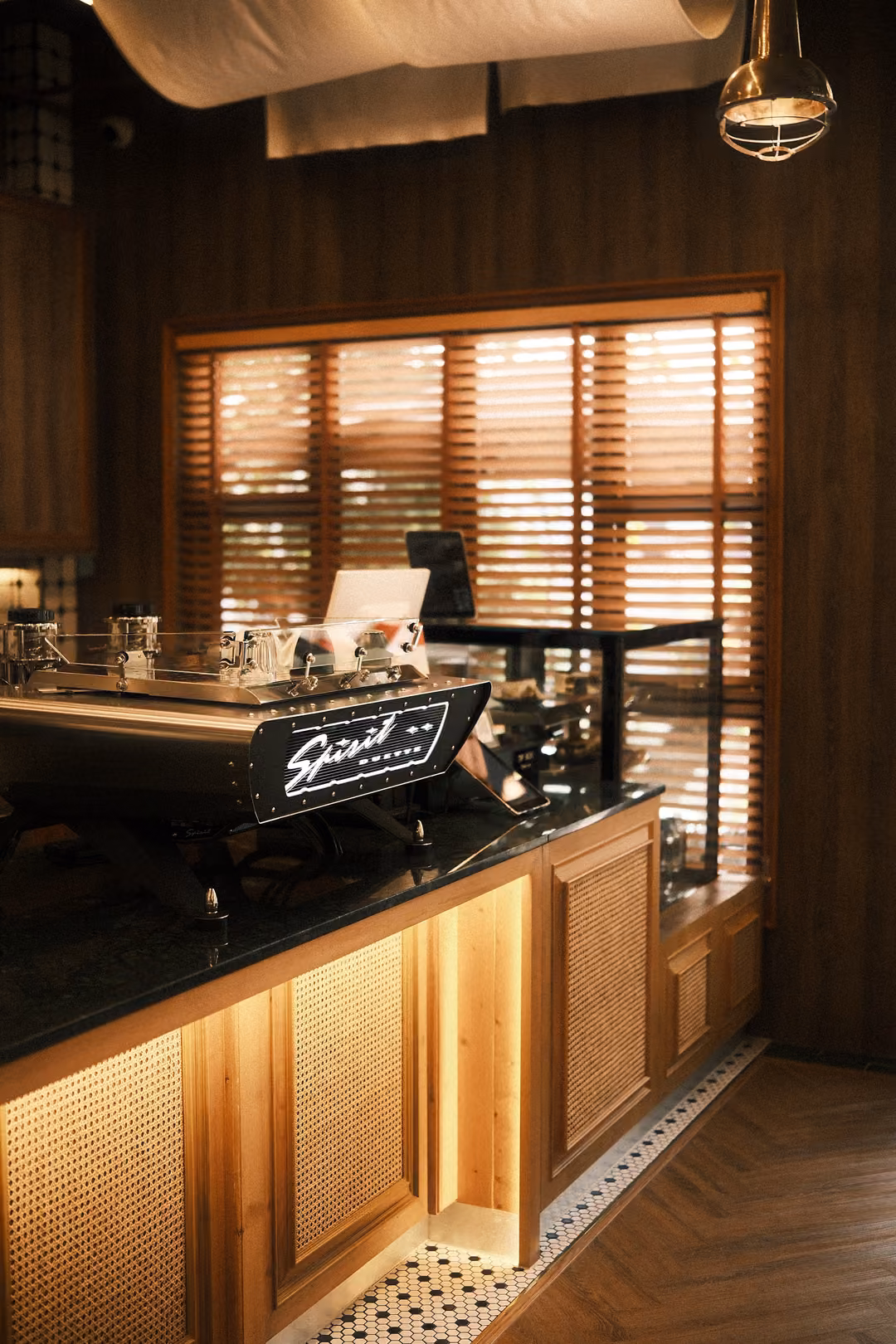 Espresso machine labelled Spirit on a dark counter with rattan panels, wooden blinds glowing behind