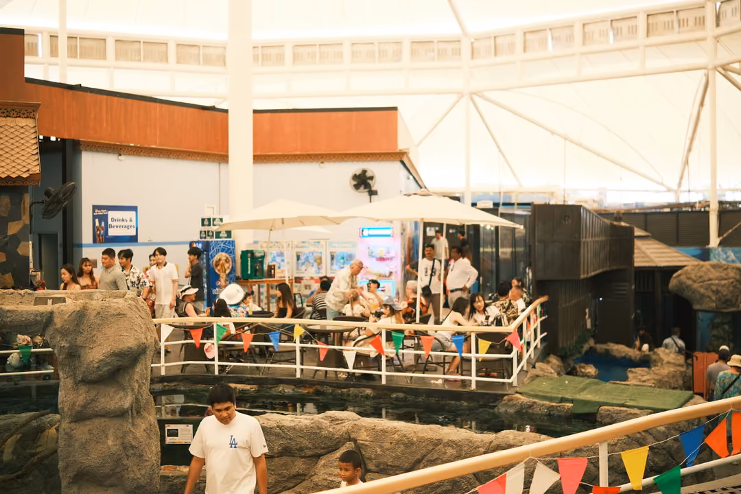 A busy open-air courtyard under a white canopy, people seated beside a pool strung with bunting