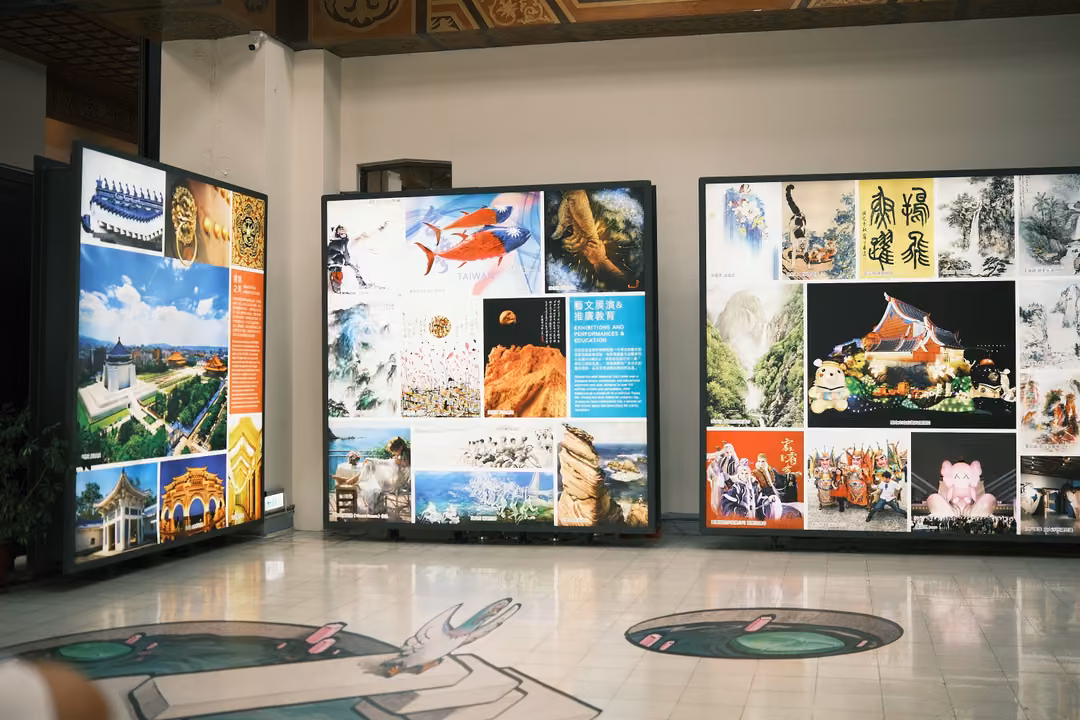 Exhibition hall with large collage panels of photos and artworks, a painted pond illusion on the floor
