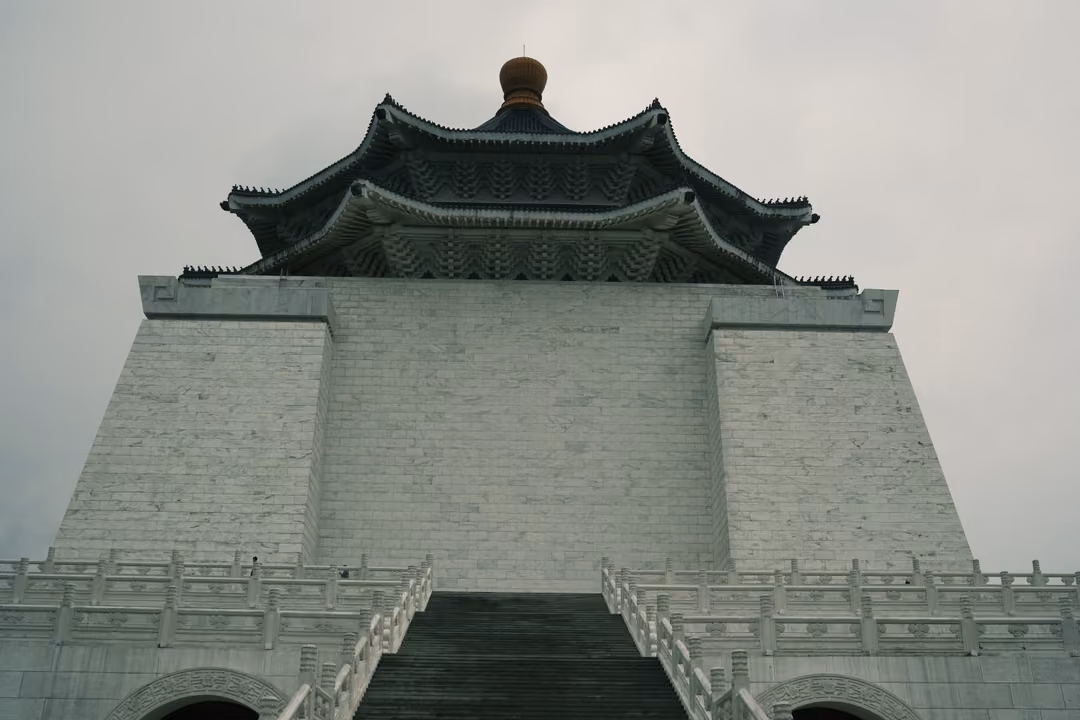 Symmetrical view of a white hall with a dark two-tiered roof and bronze finial atop a central staircase