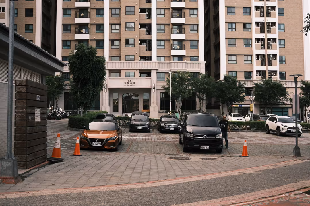 Parking area with orange traffic cones and an orange car in front of tall residential towers