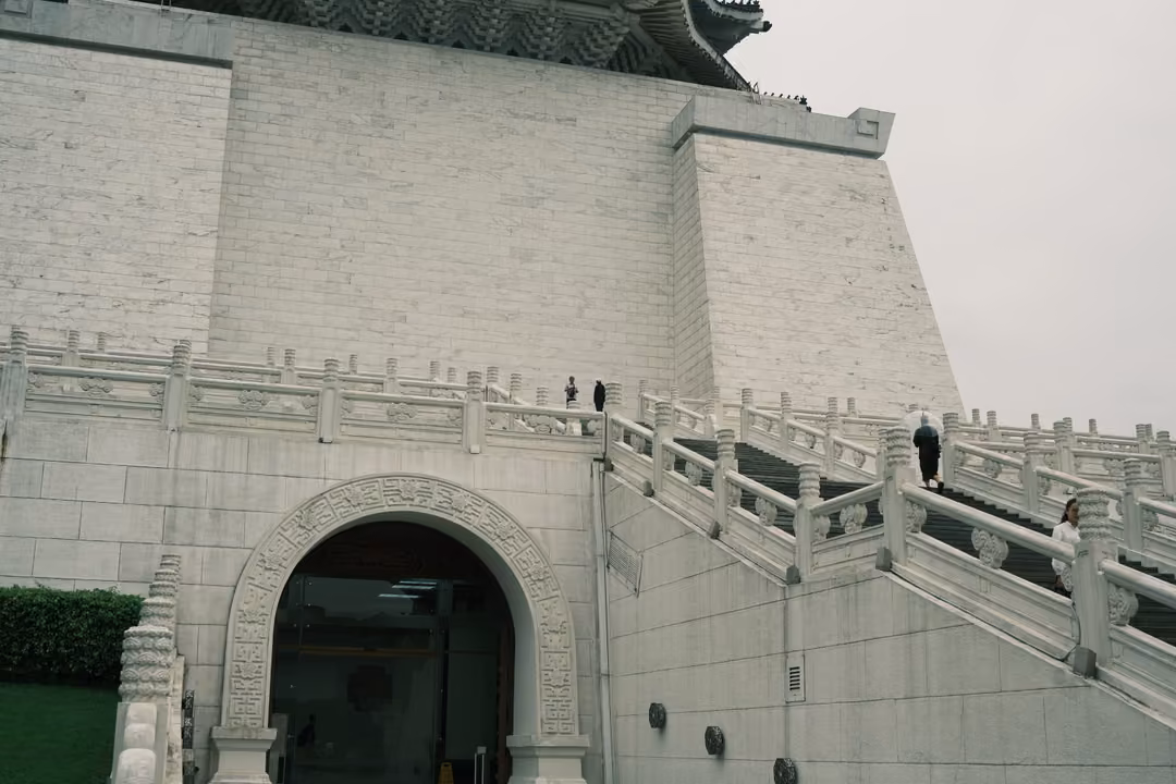 White stone hall with blue-tiled roof edge, arched doorway and broad stairs with white balustrades