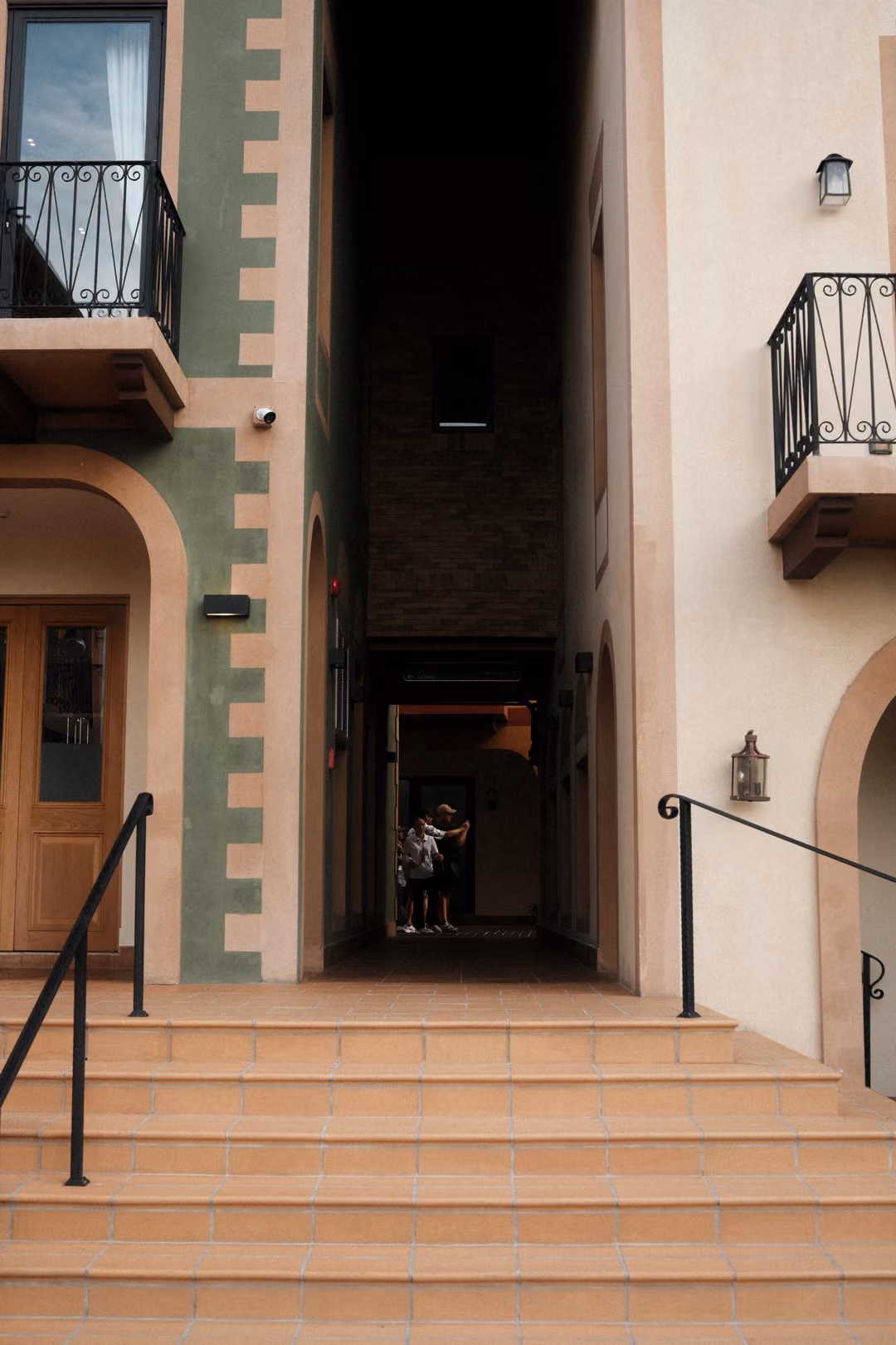 Terracotta steps leading to a narrow shadowed passage between green-trimmed and cream walls