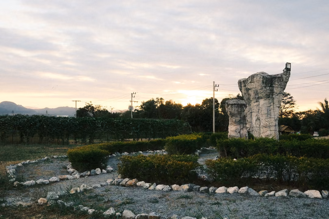 Tall weathered stone pillars rising behind clipped hedges and white stone borders, evening sky behind