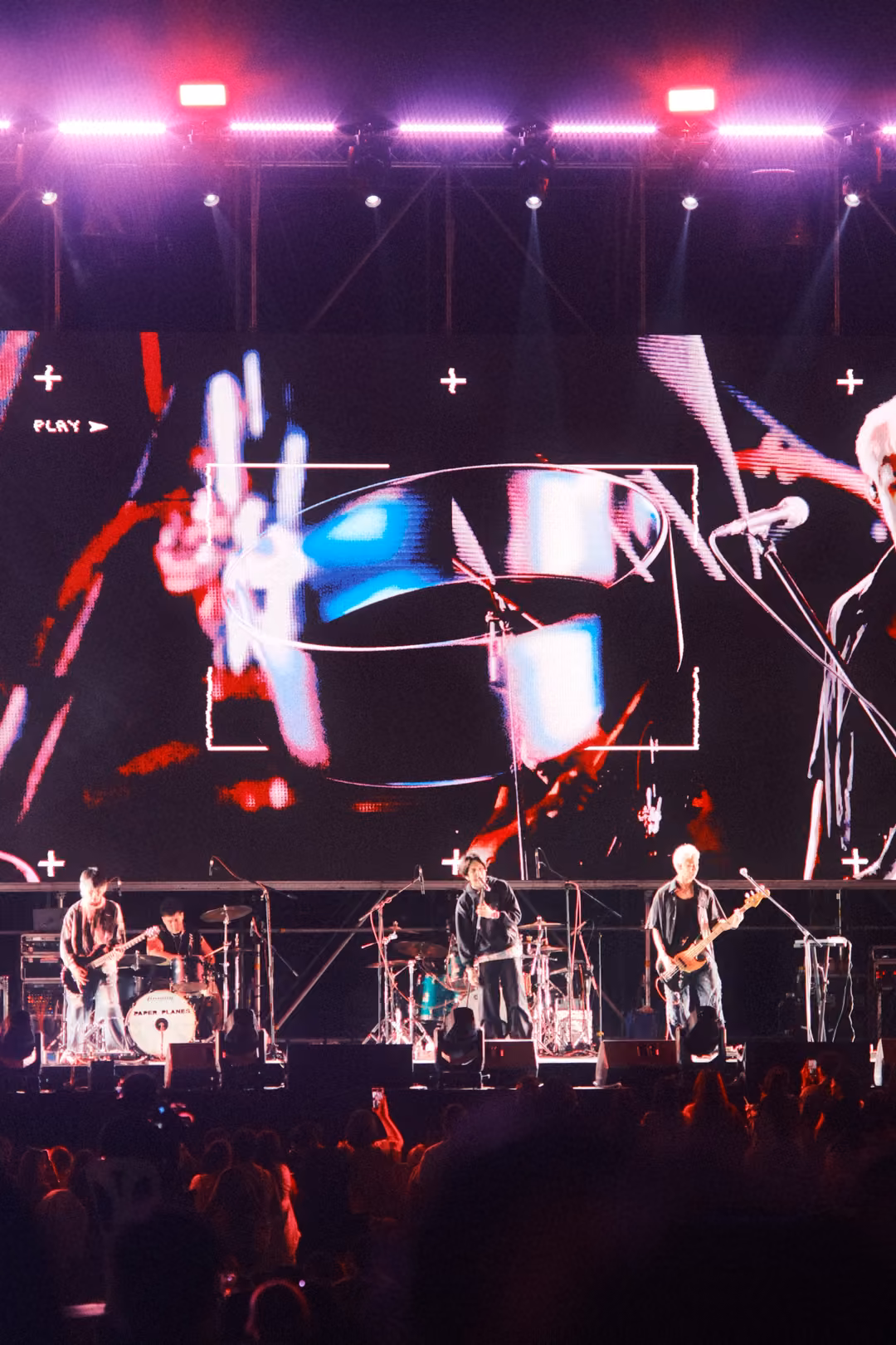 Vertical view of a screen with a fragmented ring and red streaks over a band close-up, pink lights above.